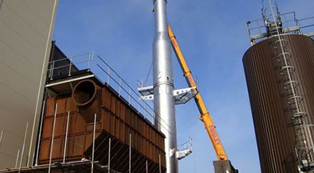 Extendable crane fixed a section of a steel chimney