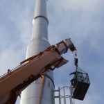 men in crane lift inspecting steel chimney