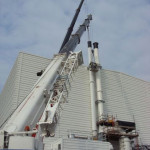 2 cranes inspections two white chimneys at side of warehouse