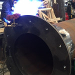 Man soldering the base of a steel chimney